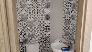 A small bathroom with a toilet, a sink, and a shower.