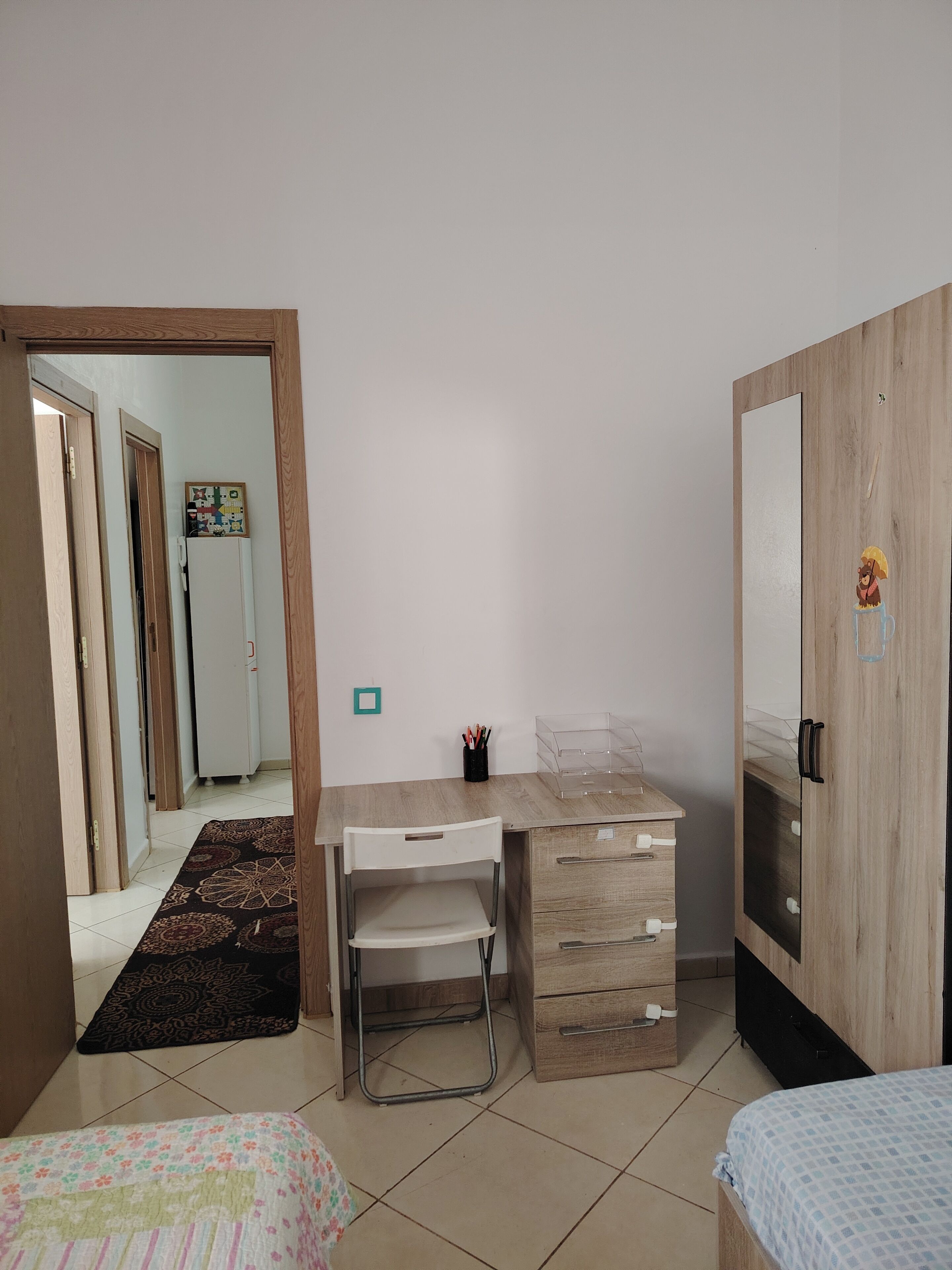 Un dormitorio con escritorio de madera, una silla, una cama y un armario.