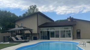 Ein Garten mit Swimmingpool, einer überdachten Terrasse und einem Haus.