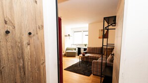 Een houten deur die leidt naar een woonkamer met een bank, een salontafel en een klein vloerkleed.