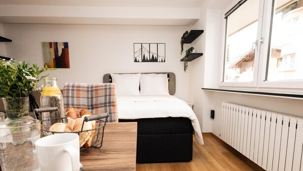 Een moderne slaapkamer met een bed, nachtkastjes, een raam en uitzicht op buiten.