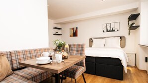 Een gezellige kamer met een bed, een bank en een ontbijttafel gedekt met ontbijtartikelen.