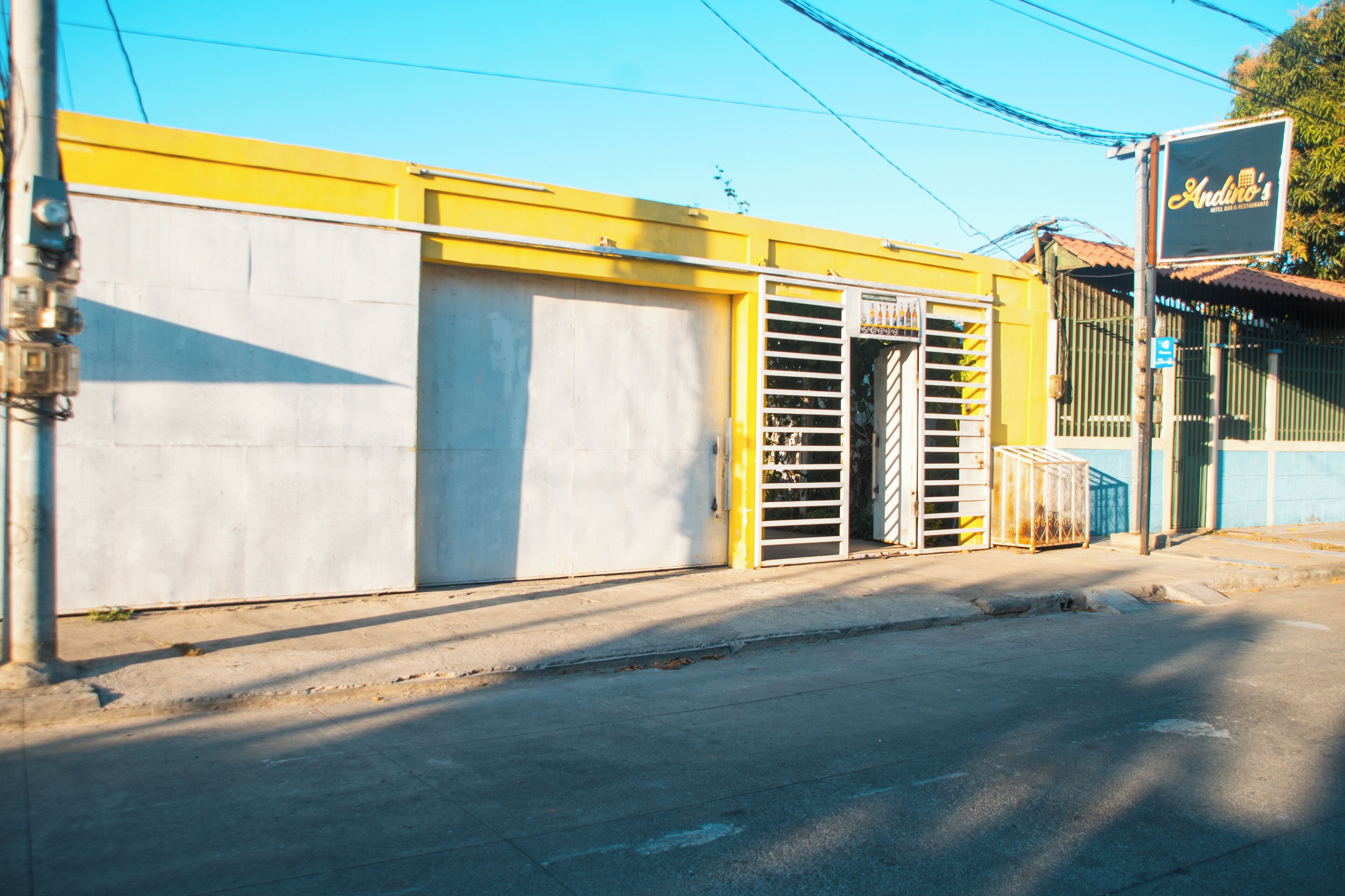 A building with a closed garage door, a metal gate, and a sign that reads "Andino's".