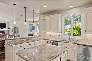 Una cocina moderna con encimeras de granito, armarios blancos y electrodomésticos de acero inoxidable.