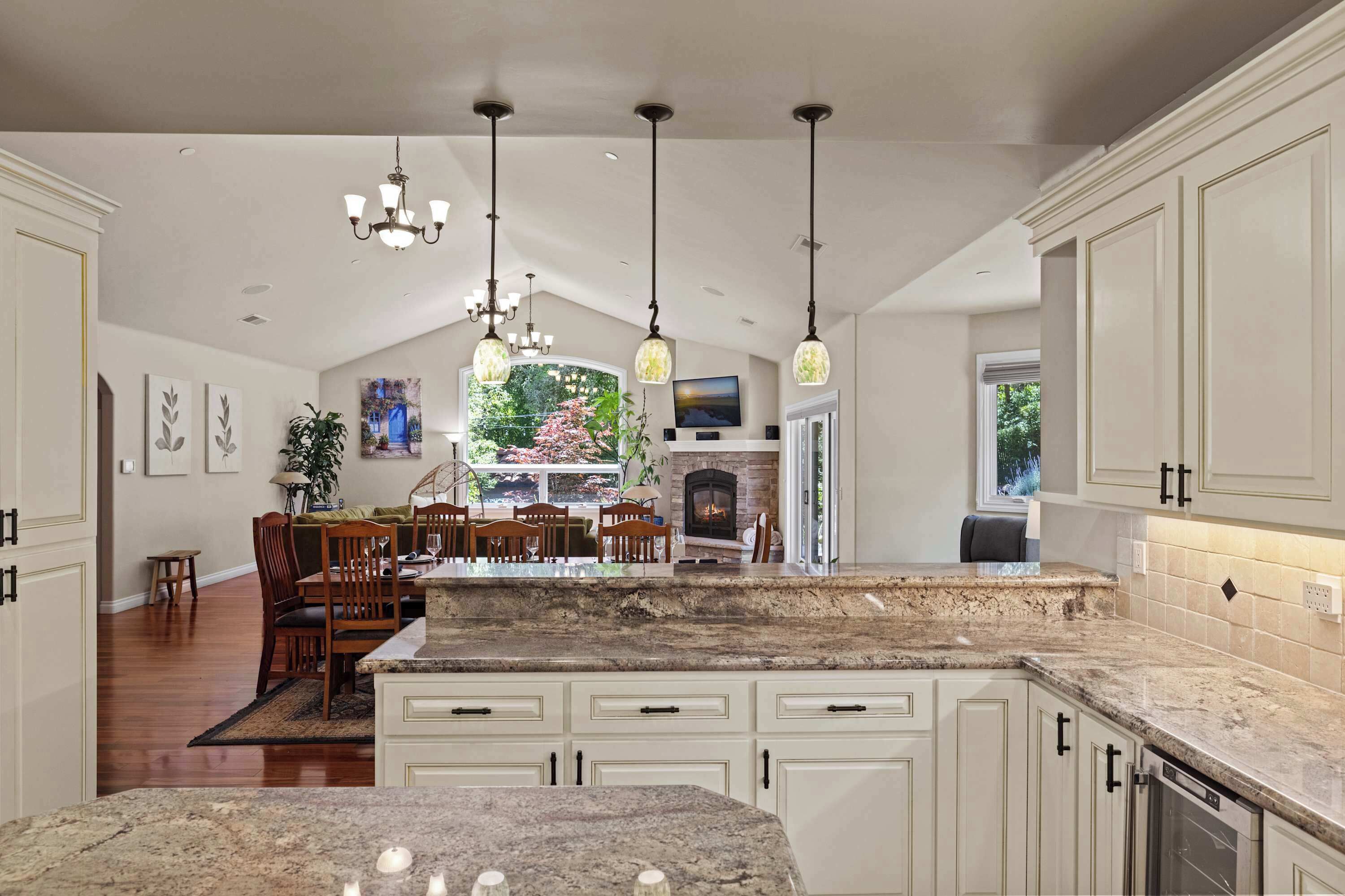 A kitchen with white cabinetry, granite countertops, and pendant lighting.