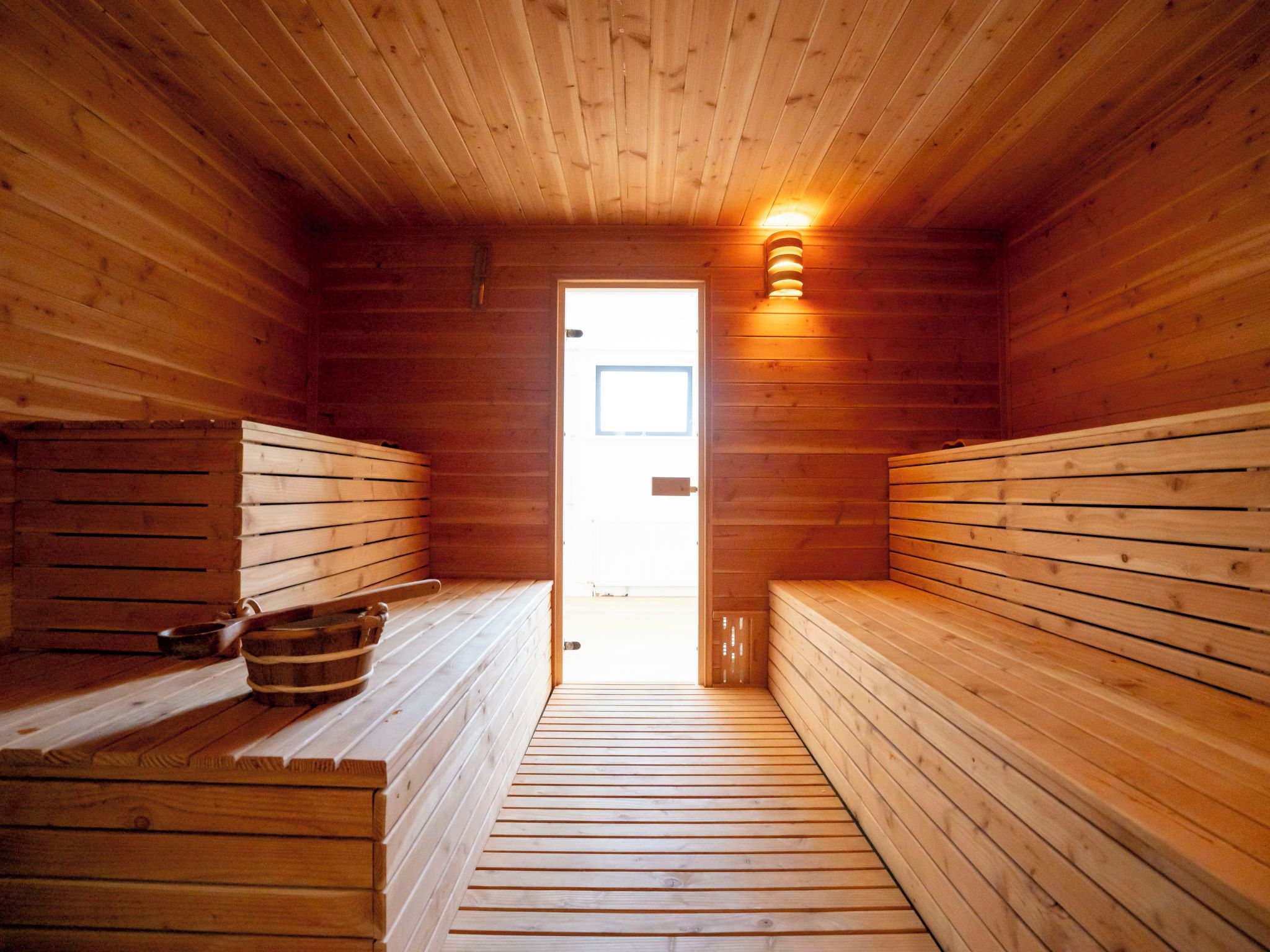 En sauna med træbænke og en bænk med en spand.