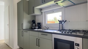 Eine moderne Küche mit grauen Schränken, einem Edelstahlherd und einem Fenster für natürliches Licht.