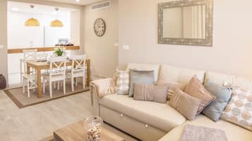 Un salon moderne comprenant un canapé, une table basse et un coin repas avec des chaises et une table.