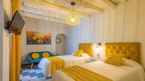 Een hotelkamer met twee bedden, een bank, een schilderij en een televisietoestel.