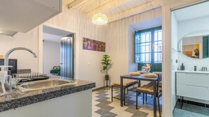 Een moderne keuken met een granieten aanrecht, een roestvrijstalen spoelbak en een eethoek met een tafel en stoelen.