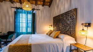 Une chambre d’hôtel avec un grand lit, un bureau, une chaise et une fenêtre avec des rideaux.