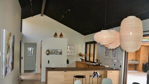 A modern kitchen with a central island, a dining area with a round table, and pendant lighting.