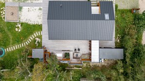 A modern house with a flat roof, a wooden deck, and a small outdoor area with a pool.