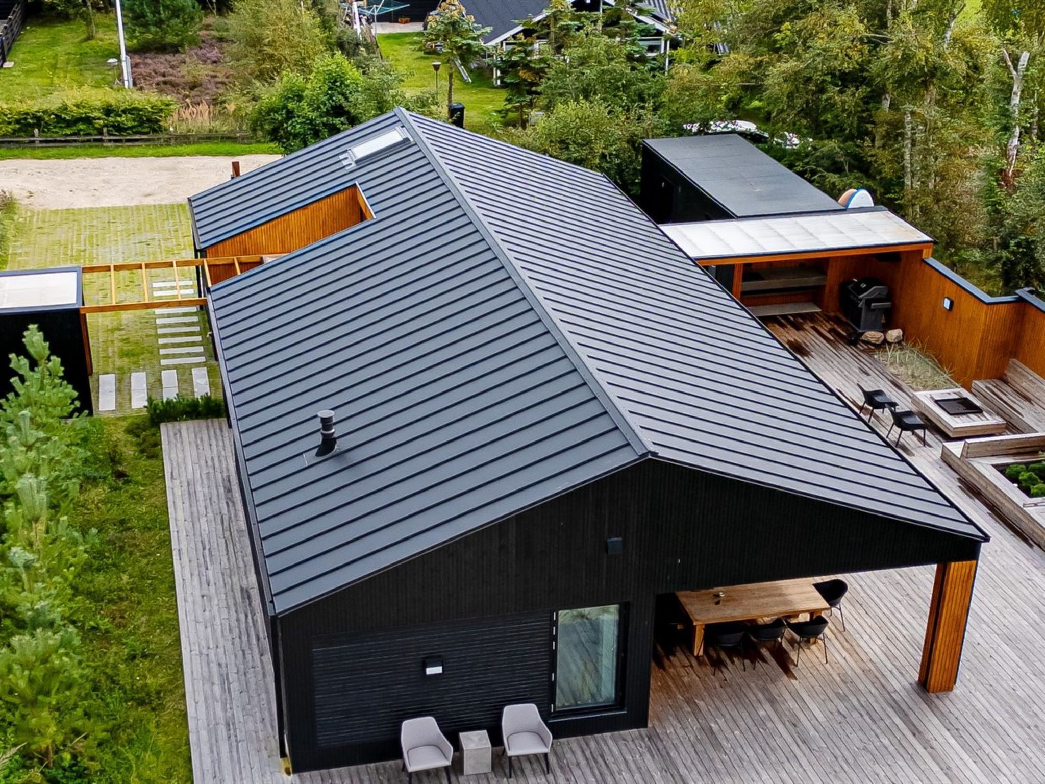 Une maison moderne avec un toit en pente, une terrasse et une grande fenêtre.