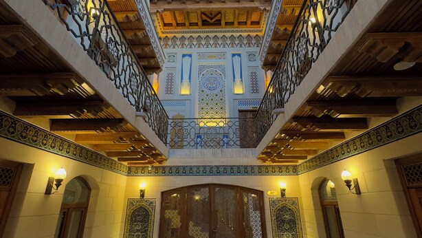 Un patio con techo de madera, detalles de azulejos intrincados y una gran puerta de madera.