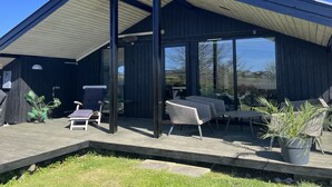 A modern house with a covered patio, large windows, and outdoor furniture.