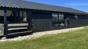 A building with a corrugated metal roof, large windows, and a wooden deck.