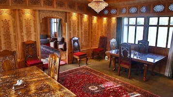 A room with ornate wooden paneling, a chandelier, a large red carpet, and a traditional wooden dining table.