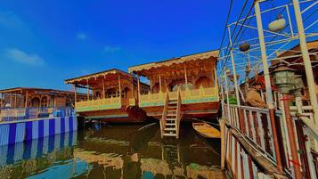 A traditional wooden boat with intricate carvings and a ladder leading to the deck.
