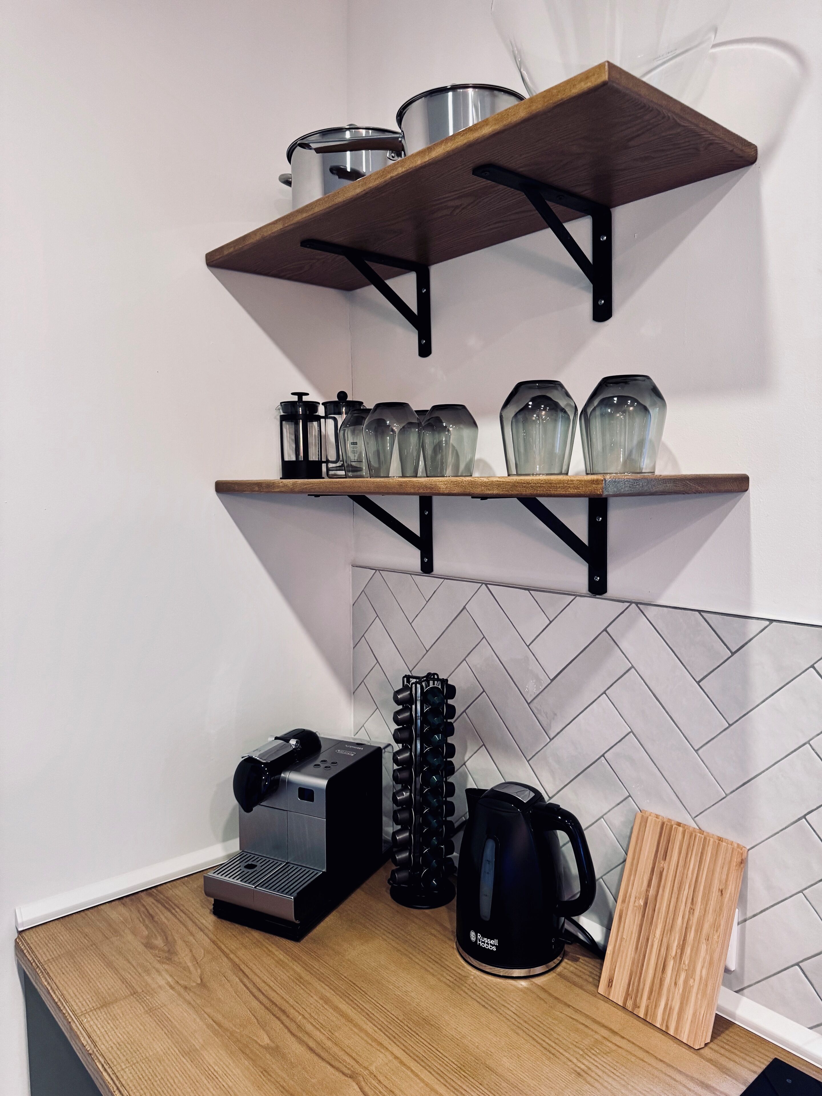 Eine Küche mit Holzböden, auf denen Töpfe und Glasbehälter, eine Kaffeemaschine und ein Wasserkocher stehen.