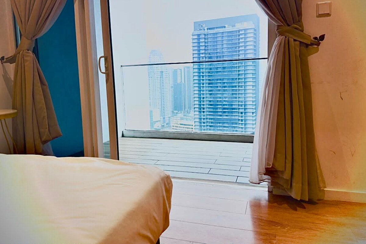 A room with a bed, curtains, and a view of high-rise buildings.