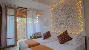 A bedroom with two beds, a decorative wall panel, and a window with curtains. - Lady Hill Hotel (Galle)