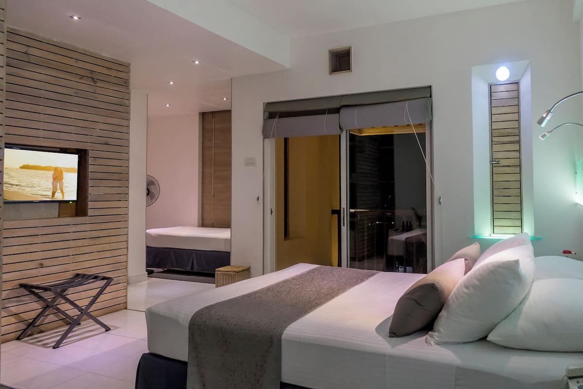 A modern bedroom with a bed, bedside table, and a TV mounted on the wall.