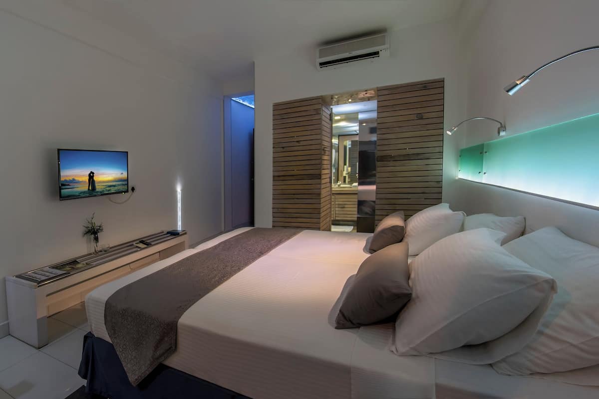 A modern bedroom with a bed, bedside tables, a TV, and a mirror.