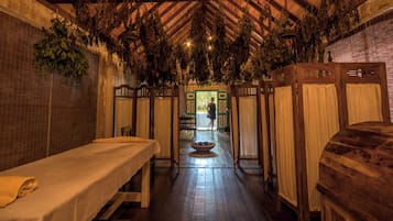 Un spa tradicional con bancos de madera, una chimenea central y plantas colgantes.