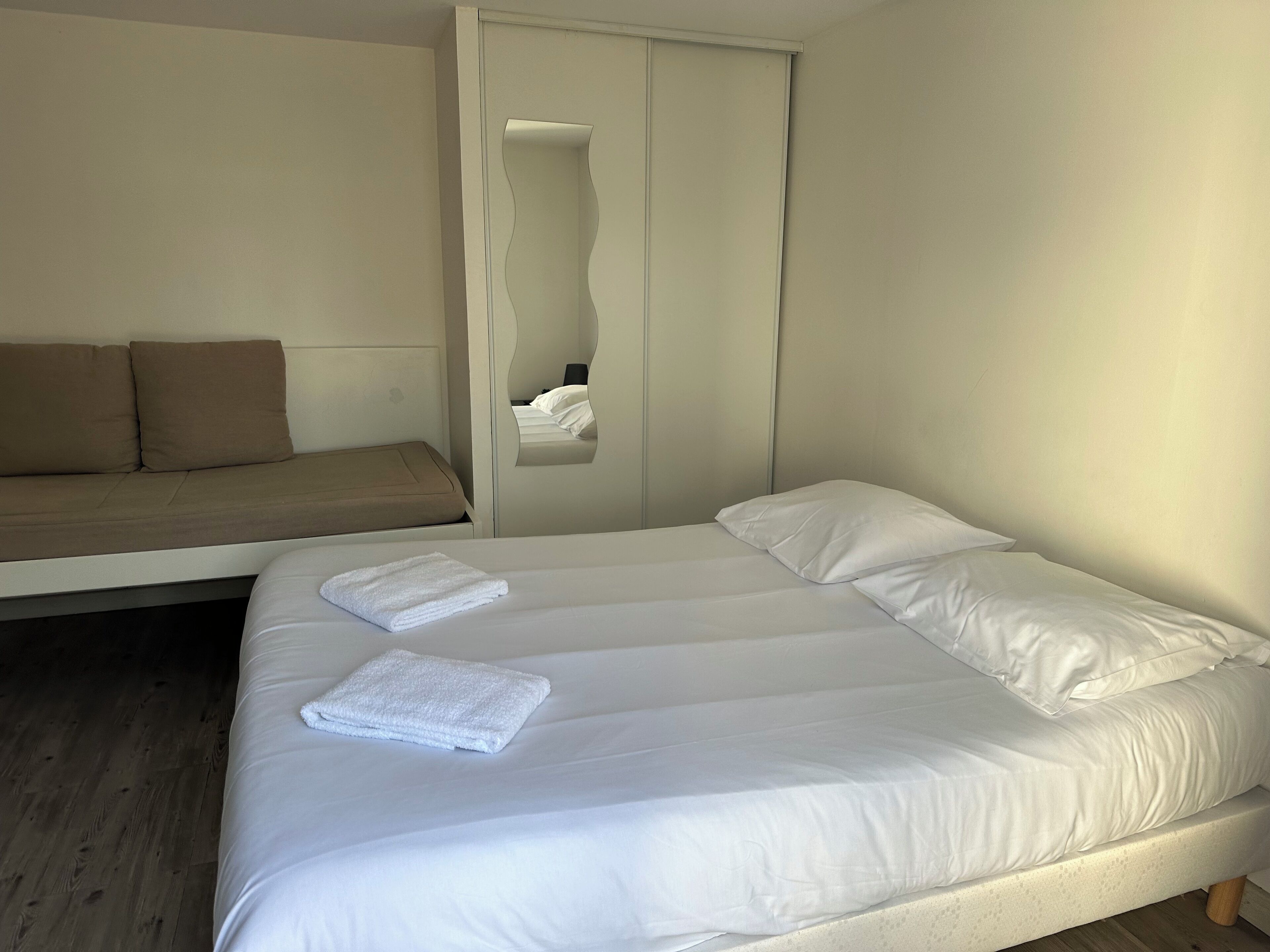A bedroom with a bed, a sofa, and a wardrobe.
