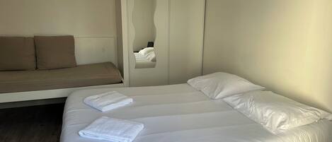 A bedroom with a bed, a sofa, and a wardrobe.