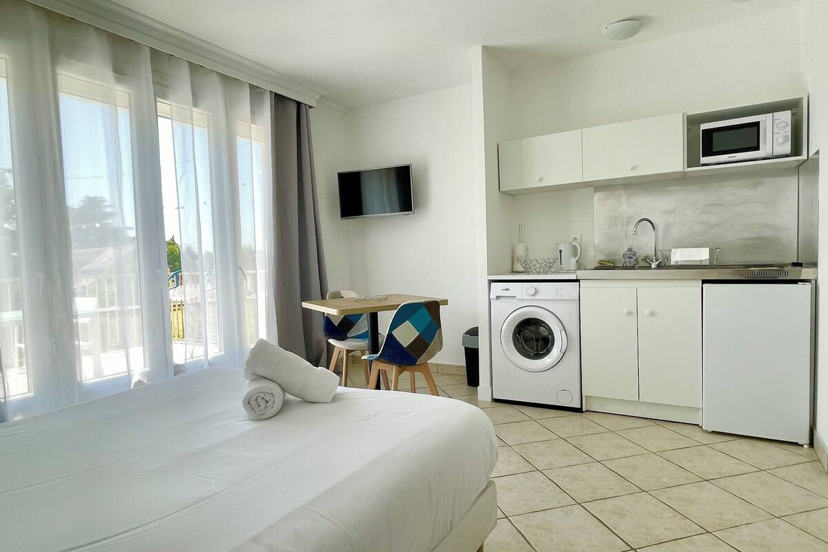 Una habitación de hotel con cama, lavadora, microondas y televisor.