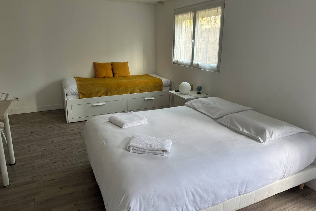 Un dormitorio con una cama grande, una mesita de noche con lámpara y una ventana con cortinas.