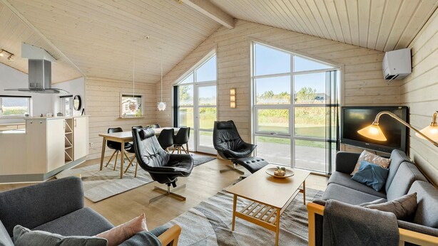 A spacious living area with a large window, a dining table, and a sofa. - Amazing home in Tarm with sauna (Tarm)