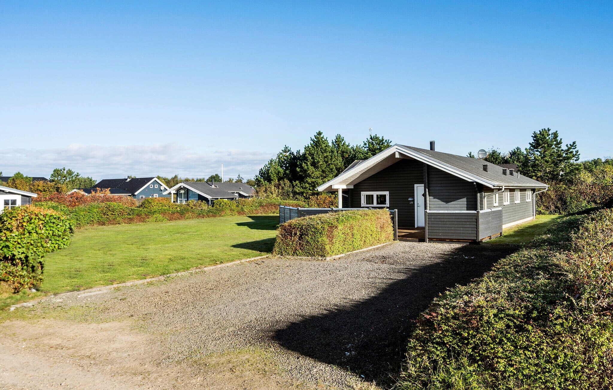 A row of modern cabins with a gravel driveway leading to a grassy area.