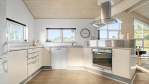 A modern kitchen with a central island, stainless steel appliances, and large windows providing natural light. - Amazing home in Tarm with sauna (Tarm)