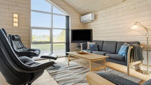 A modern living room with a large window, a flat-screen TV, a sofa, a coffee table, and a leather chair. - Amazing home in Tarm with sauna (Tarm)