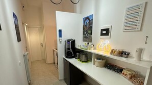 A modern kitchen with a built-in coffee machine, a bicycle-shaped light fixture, and a bike-themed wall decoration. - Bed&BikeRome ANGELICO  (Rome)