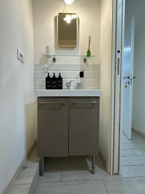 Un baño moderno con un mostrador blanco, dos armarios, un espejo y una lámpara.