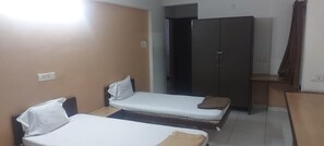 A small, clean room with two single beds, a wardrobe, and a desk. - Ozone Guest House (Pune)