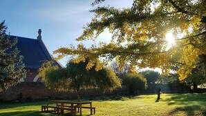 Un espace extérieur verdoyant avec une table de pique-nique et un bâtiment en briques en arrière-plan.