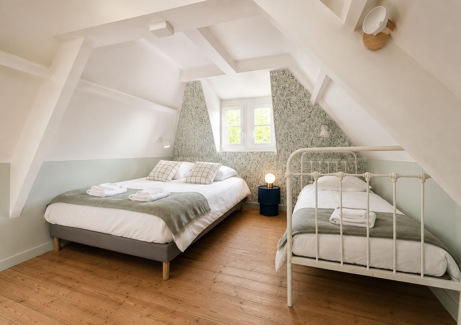 Een slaapkamer met twee bedden, een dakraam en een decoratieve wand.