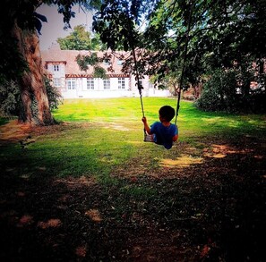 A child on a swing in a grassy area with a building in the background. - Belle Demeure Picarde Avec son Parc de 5000m2 (le ployron)