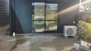 A building with a closed shutter door, a small air conditioning unit, and a gravel ground. - A Gem In Ascot is situated in Invercargill. (Invercargill)