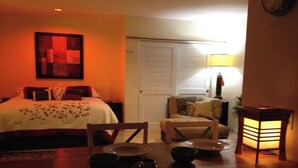 Una habitación acogedora con una cama, una mesa de comedor con sillas y una lámpara.