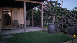 Un espacio al aire libre cubierto con sillas, una jardinera grande y una escalera que lleva a una terraza de madera.