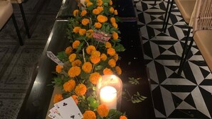 Un lungo tavolo con fiori di calendula e candele, circondato da poltrone e divani in vimini.