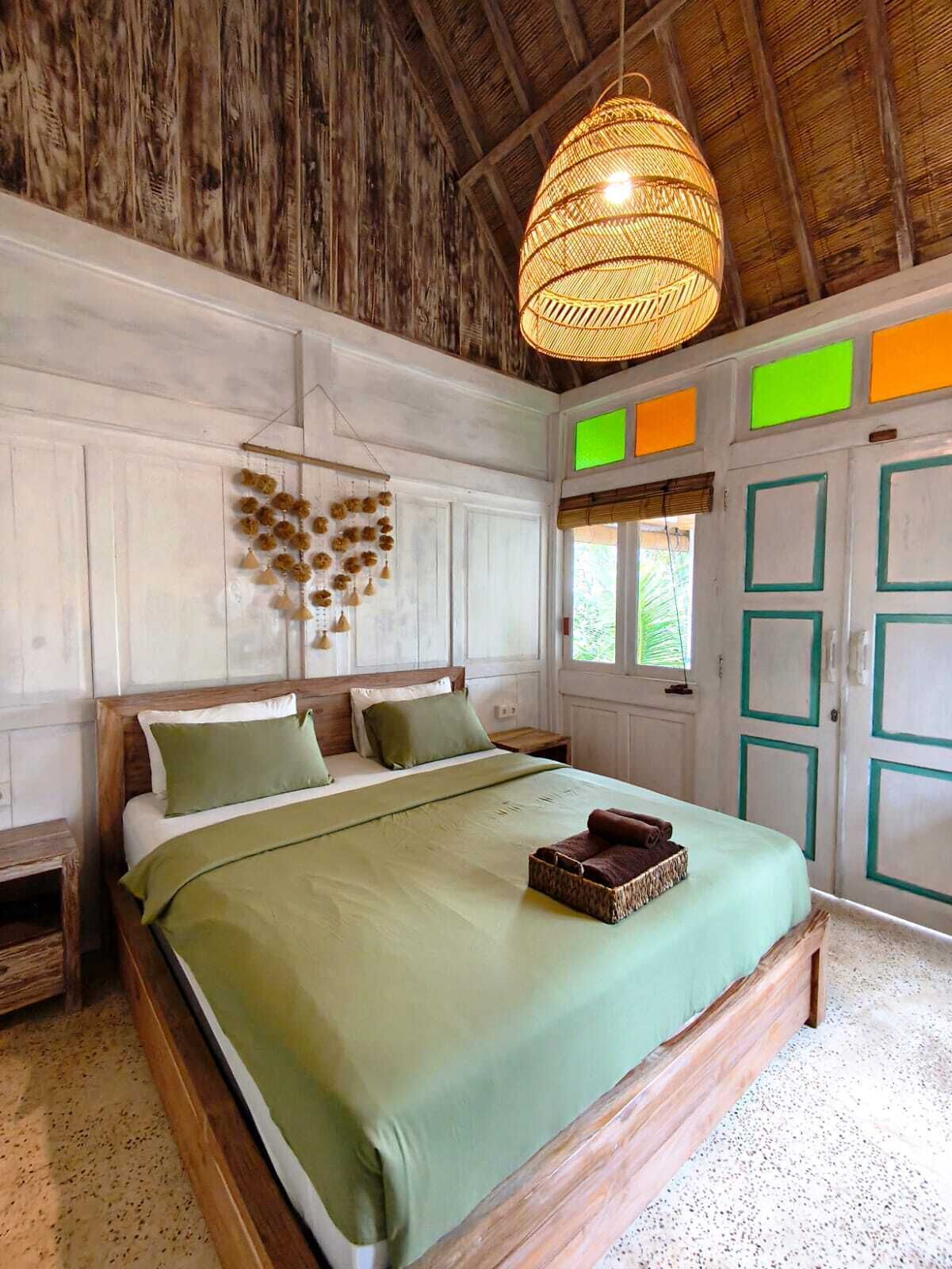 A bedroom with a wooden bed, a hanging light fixture, and a wall-mounted decoration.