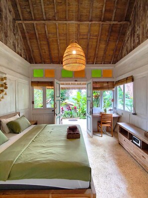 A room with a bed, a desk, and a view of greenery outside. - Purwa Ijen (Banyuwangi)