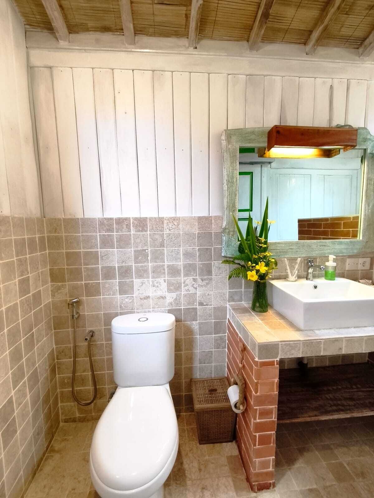 A bathroom with a white toilet, a sink with a mirror, and a shower.